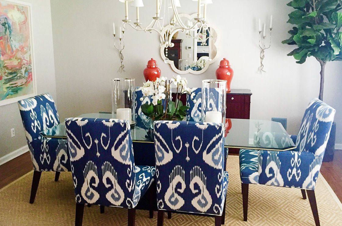 A dining room with blue and white chairs and a glass table