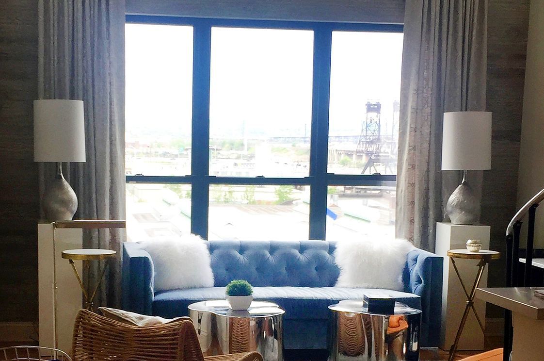 A living room with a blue couch and a large window.