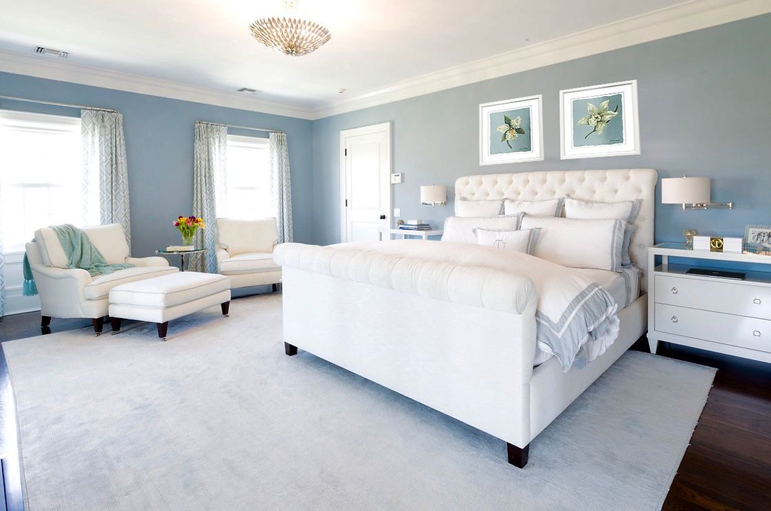 A bedroom with a king size bed , chair , nightstand , and ottoman.