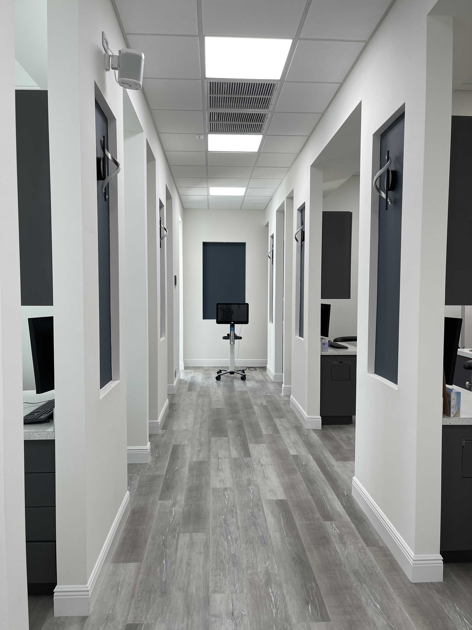 A long hallway in a dental office with a chair in the middle.