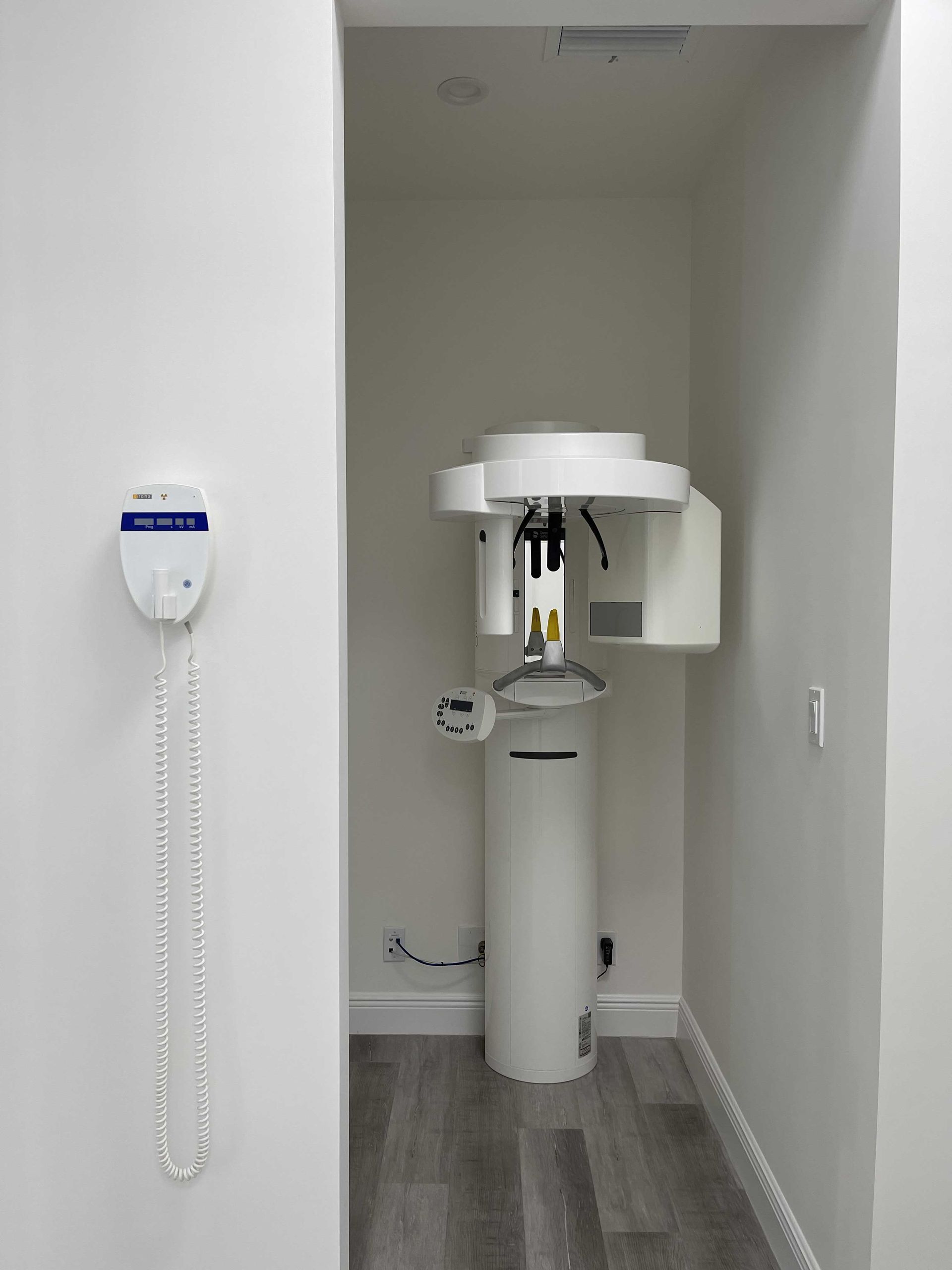 A dental office with a x-ray machine and a phone hanging on the wall.