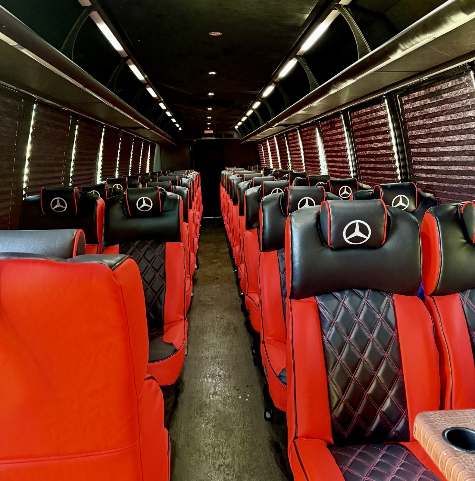 Interior of a luxury shuttle bus with black leather diamond-stitched seats and dark ceiling lighting.