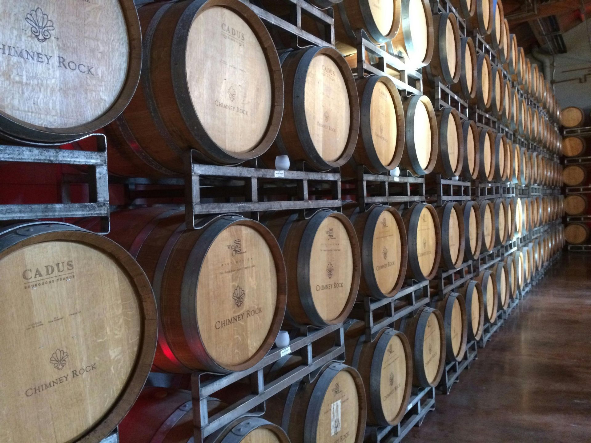 A row of wooden wine barrels stacked on top of each other in a wine cellar.