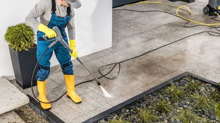 Noble Washing LLC | A man is cleaning a patio with a high pressure washer.