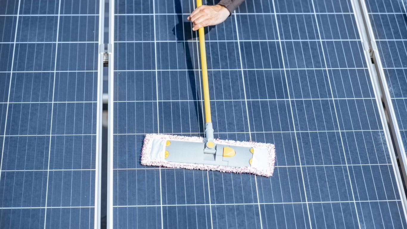 Noble Washing LLC | A person is cleaning a solar panel with a mop.