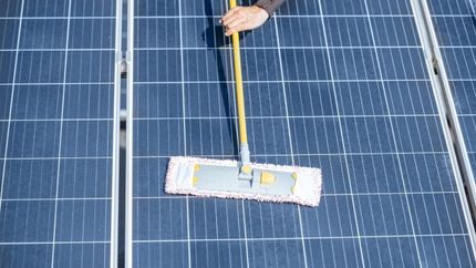 Noble Washing LLC | A person is cleaning a solar panel with a mop.