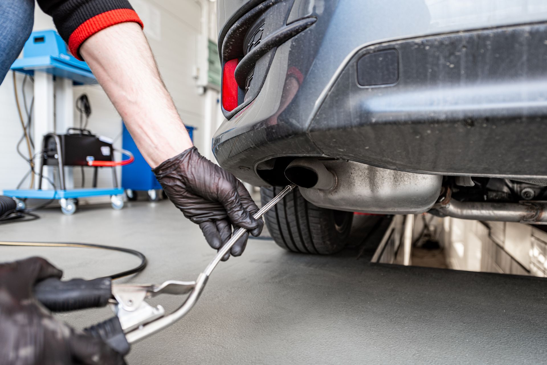 A person is working on the exhaust pipe of a car.
