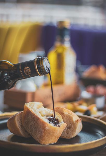 A bottle of wine is being poured on a piece of bread on a plate.