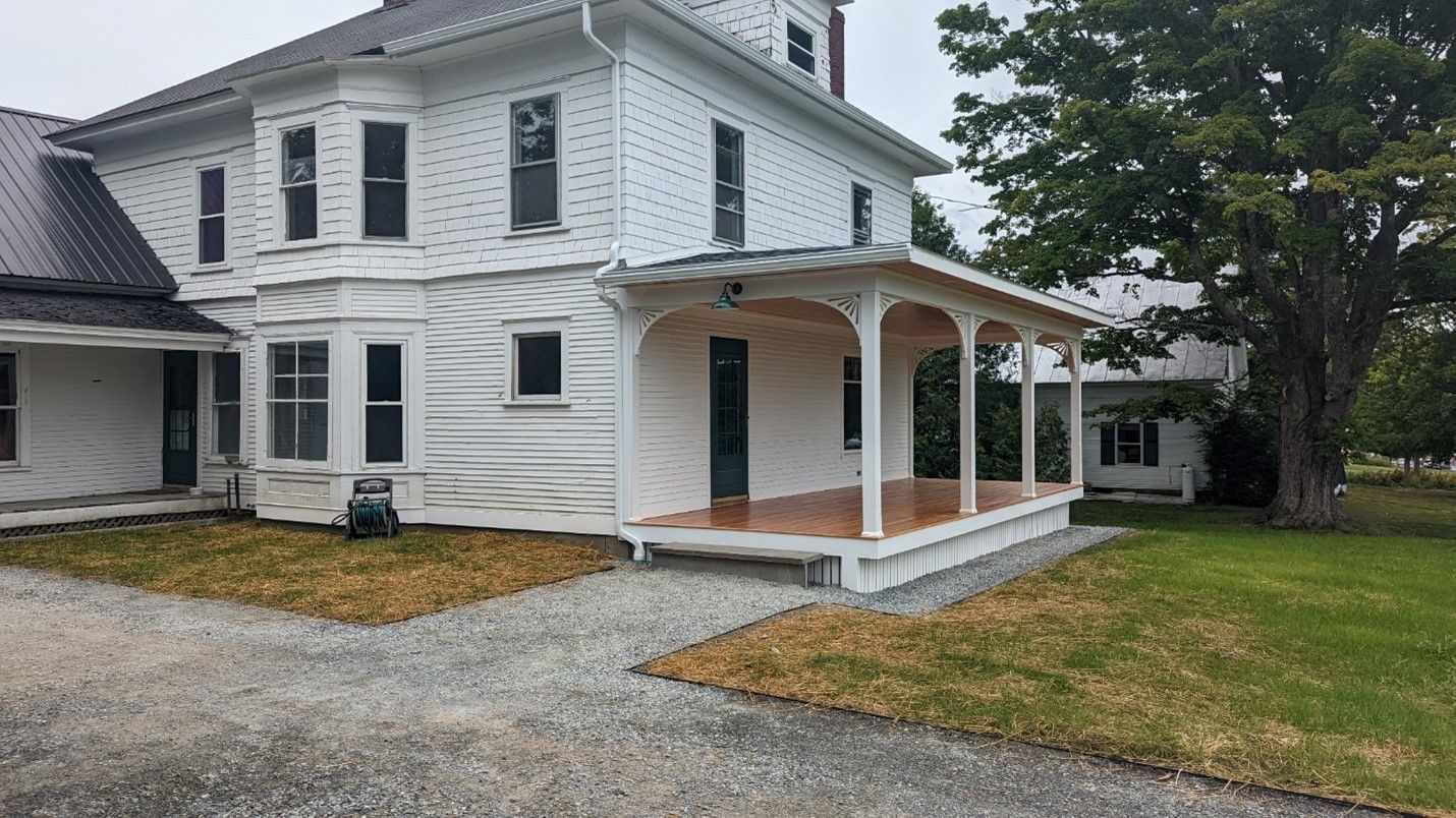 A covered porch with beautiful wood flooring as part of a residential remodel by Juggernaut Construction Company