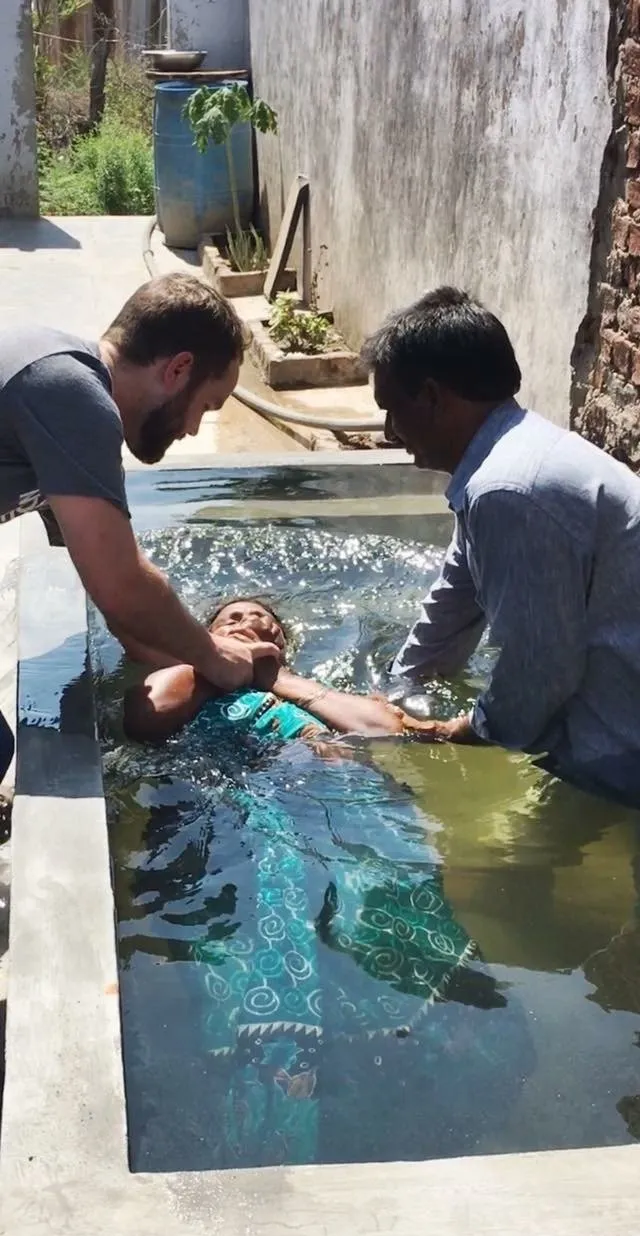 A man is baptizing a woman in a pool of water.