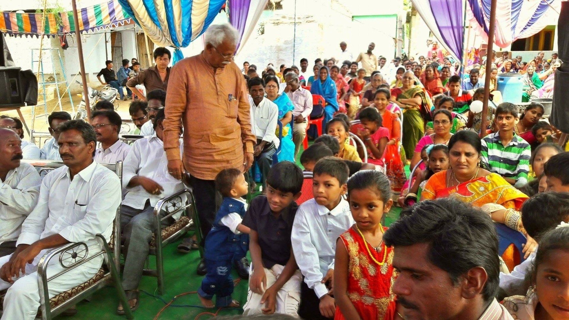 A large group of people are sitting under a tent.