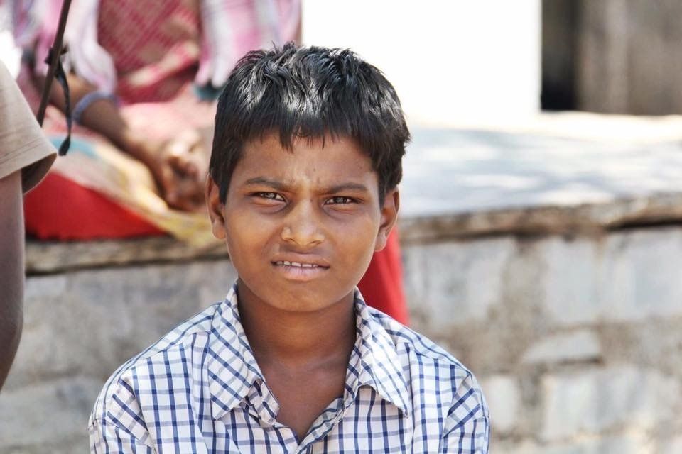 A young boy in a plaid shirt is looking at the camera