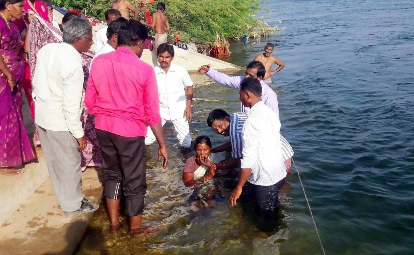 A group of people are standing around a body of water.