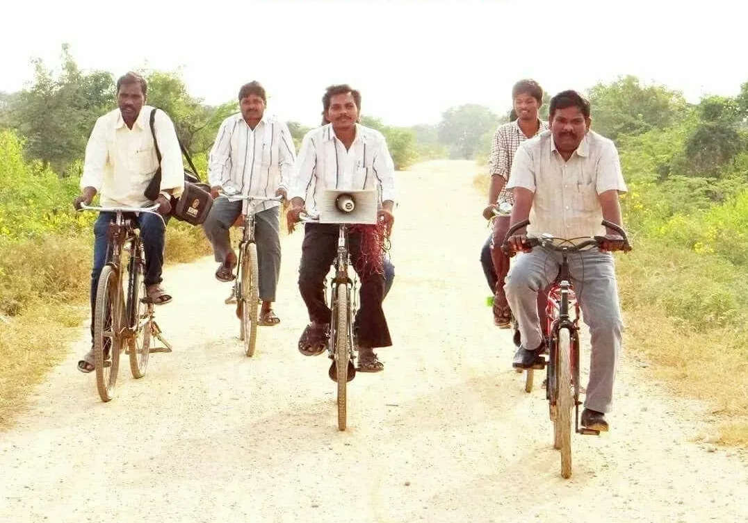 A group of men are riding bicycles down a dirt road.