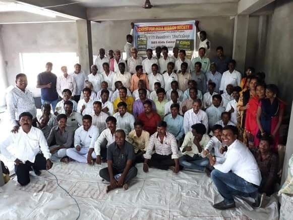 A large group of people are sitting on the floor in a room.