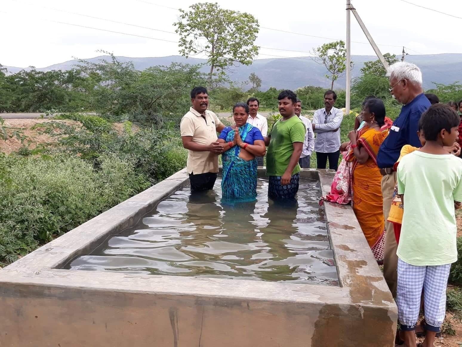 A group of people are standing around a pool of water.