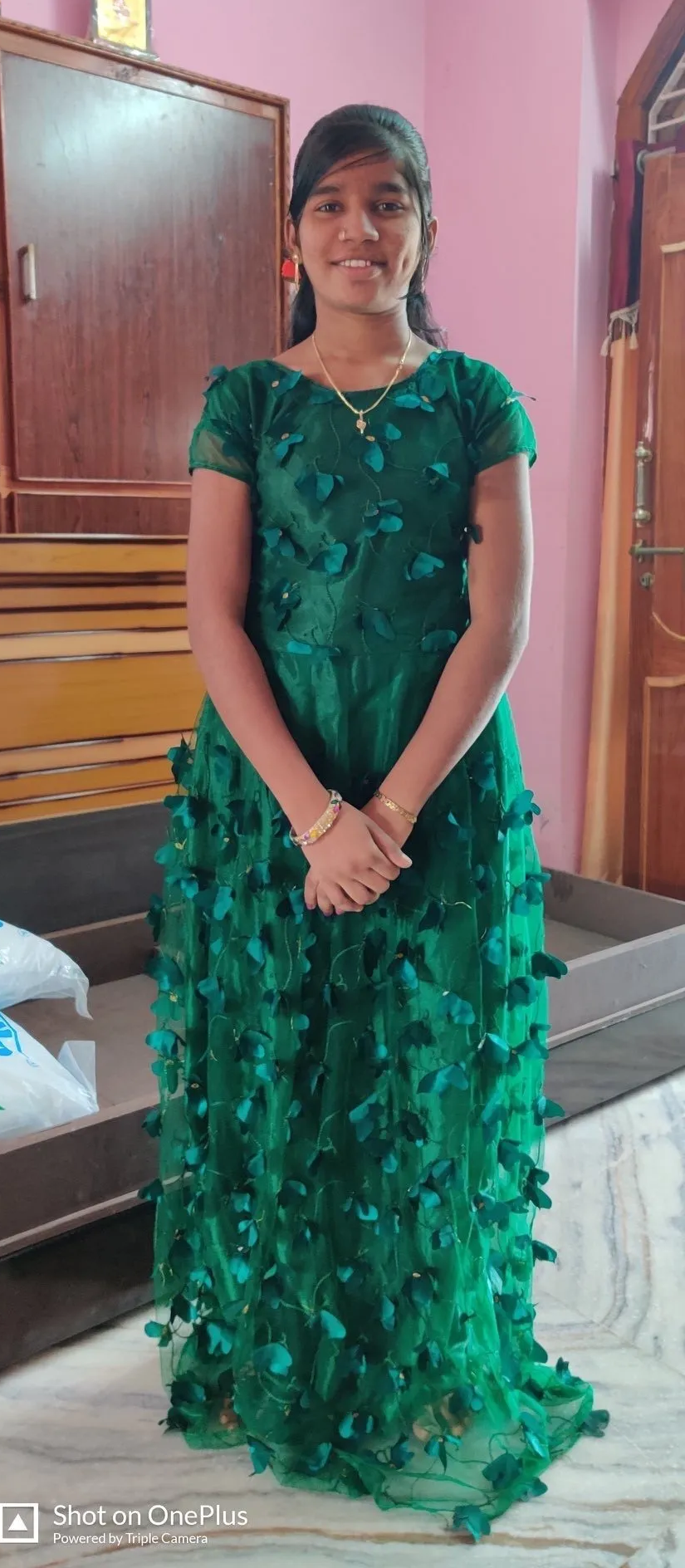 A young girl in a green dress is standing in a room.
