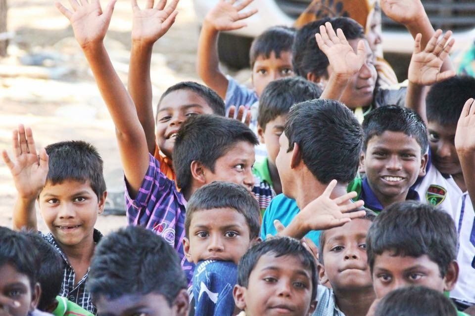 A group of children are raising their hands in the air