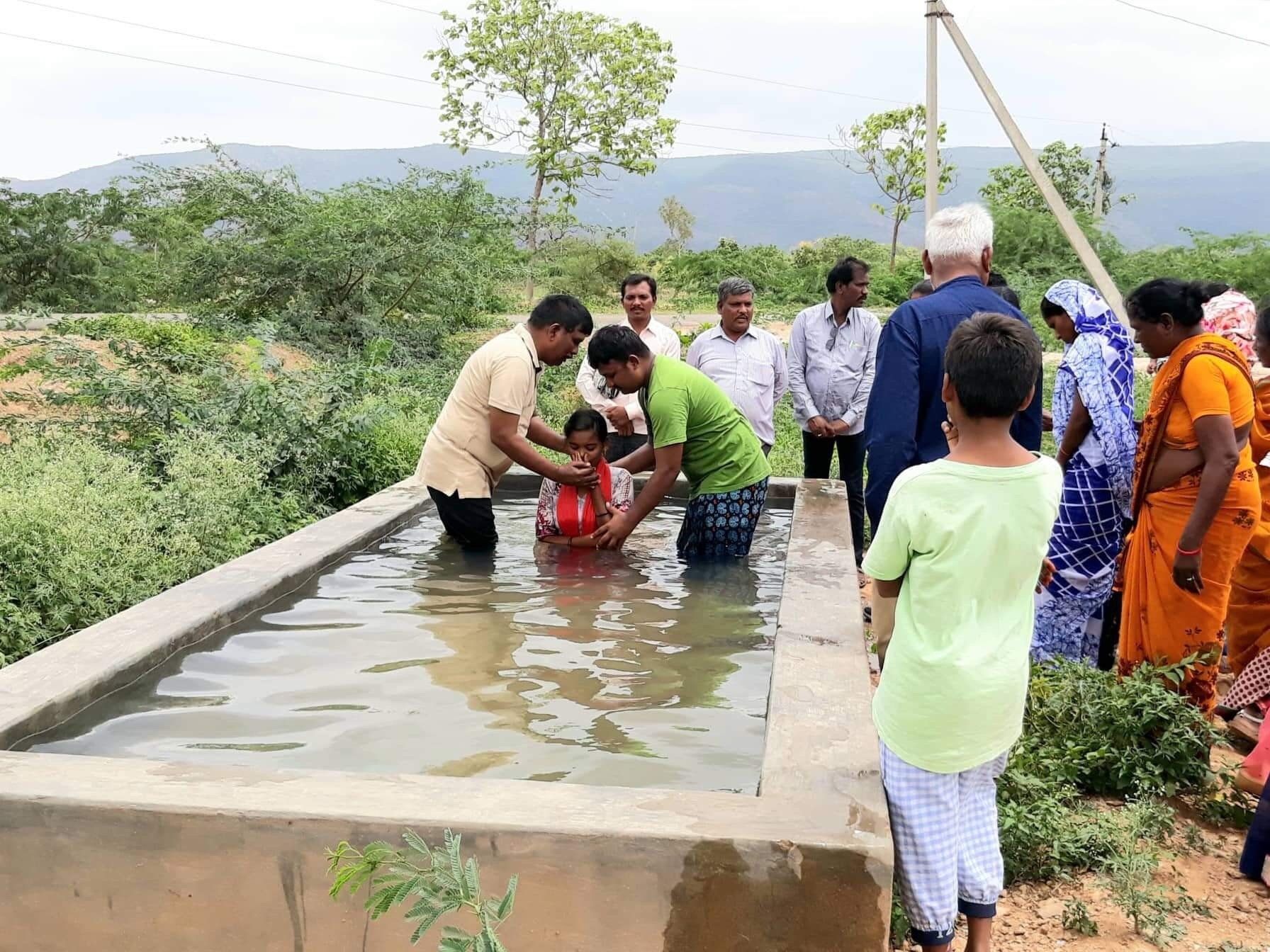 A group of people are standing around a pool of water.