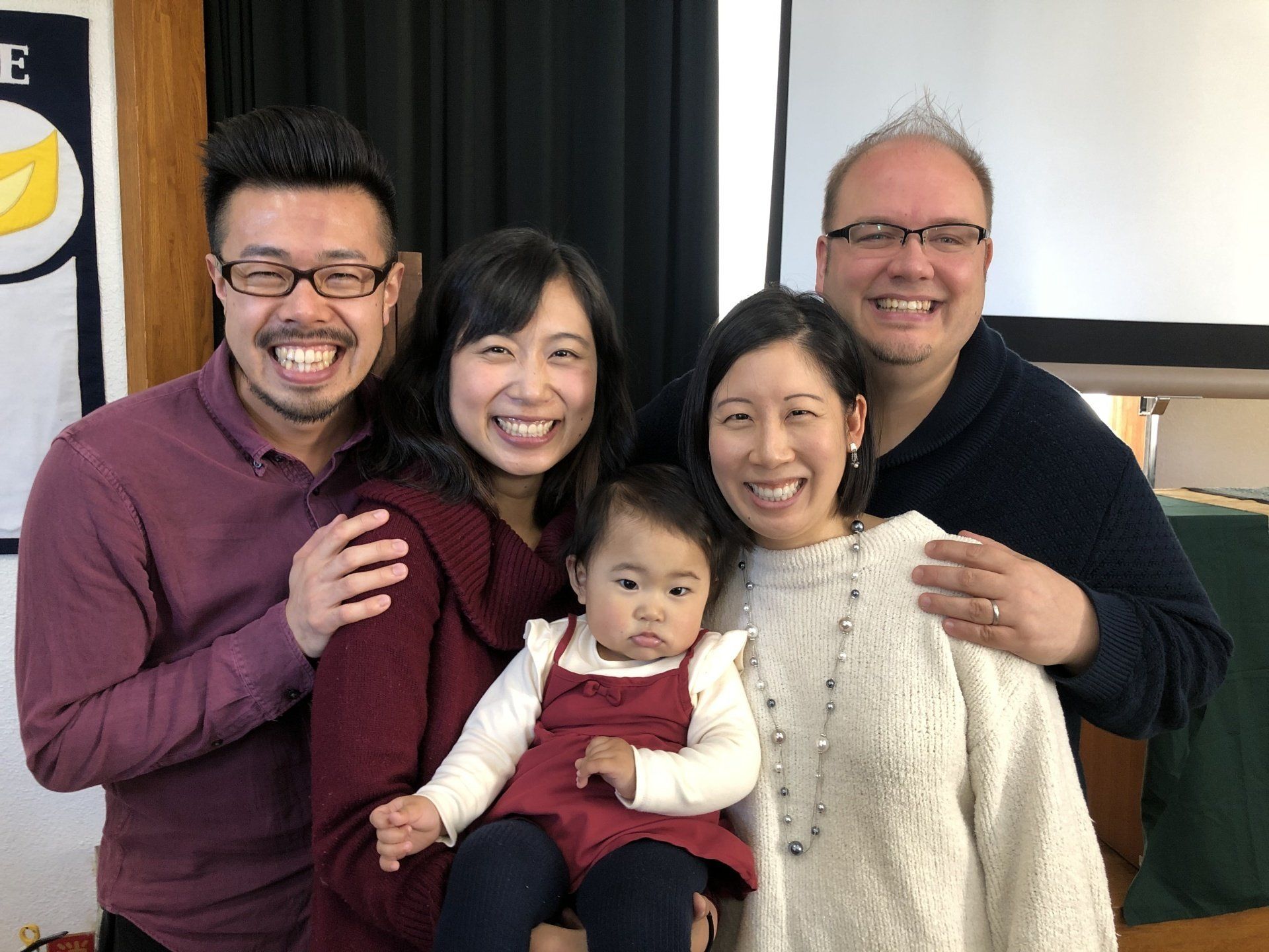 A group of people are posing for a picture with a baby.
