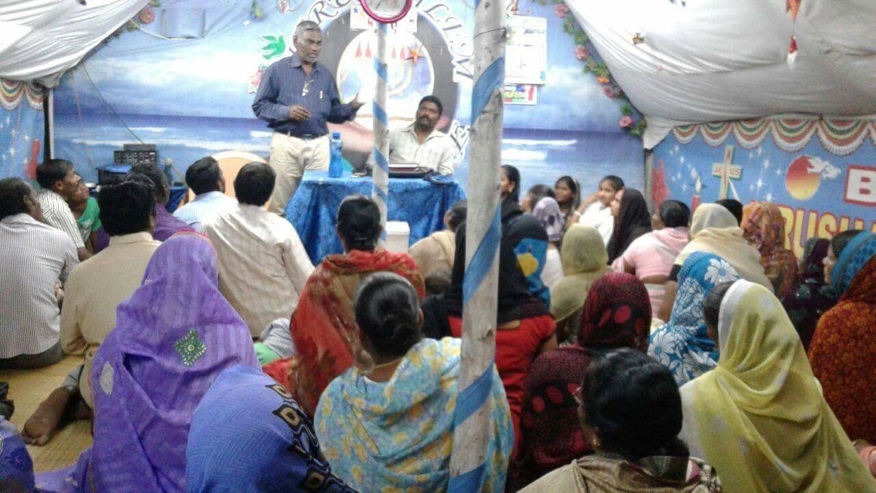 A group of people are sitting in front of a man giving a speech.