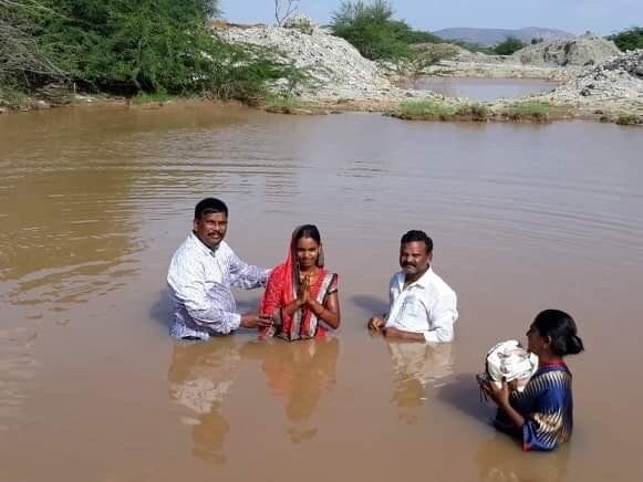 A group of people are standing in a body of water.