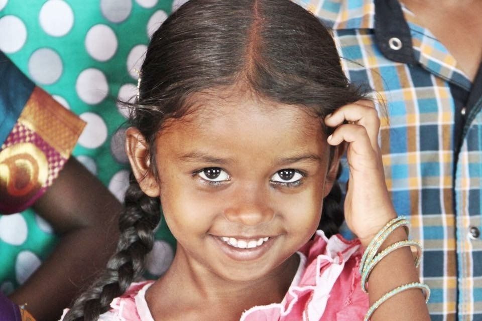 A little girl in a pink dress is smiling for the camera