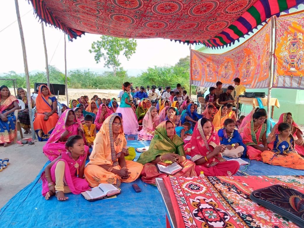 A large group of people are sitting under a tent.