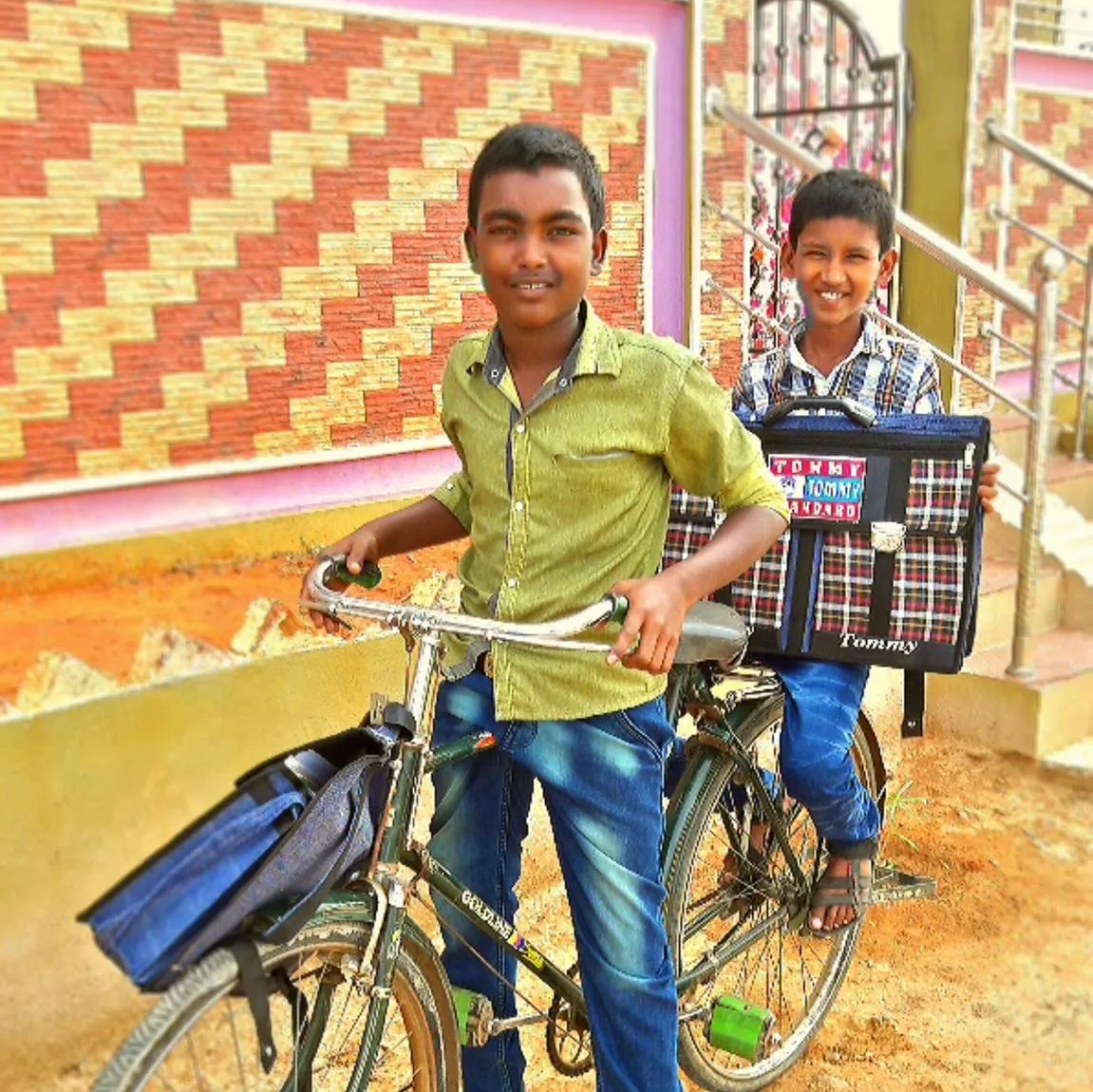Two young boys are standing next to a bicycle and one of them is holding a bag that says ' tesco '