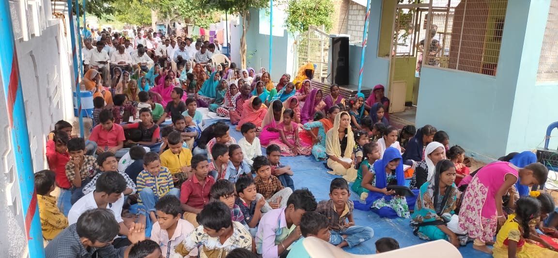 A large group of people are sitting on the floor in a room.