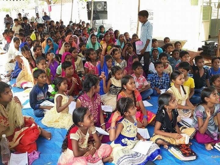 A large group of children are sitting on the floor.