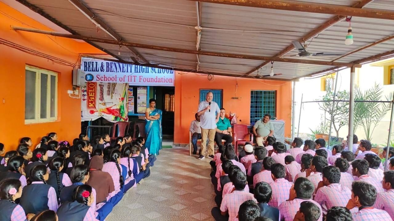 A group of people are sitting in front of an orange building.