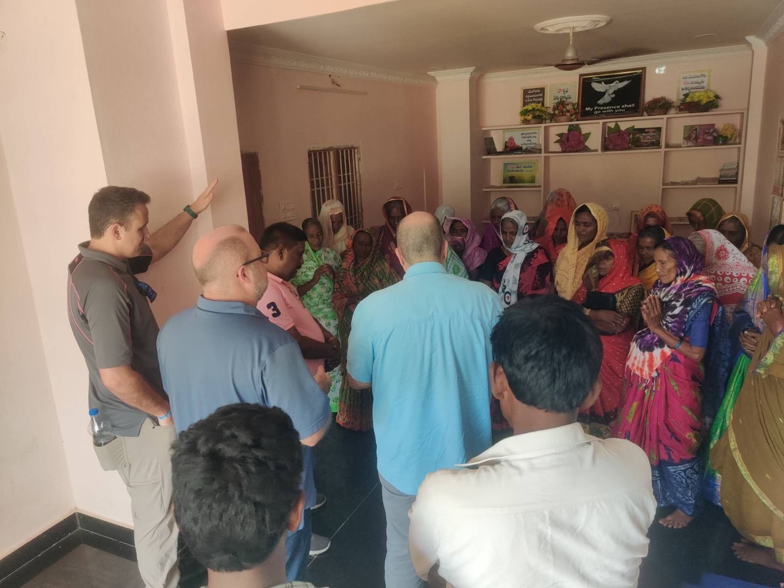 A group of people are standing in a room talking to each other.