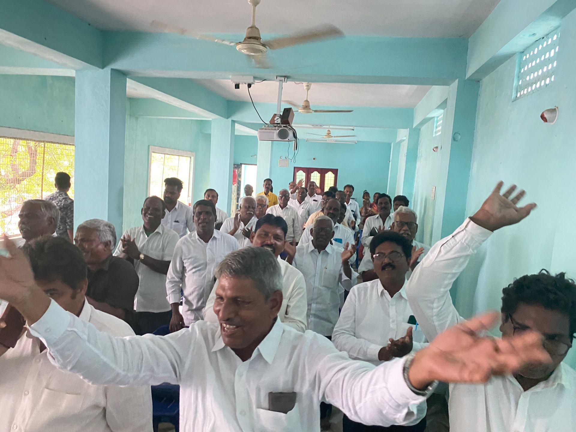 A group of men are standing in a room with their arms outstretched.