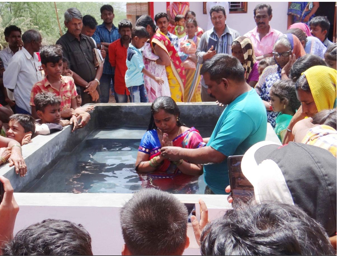 A group of people are watching a woman being baptised