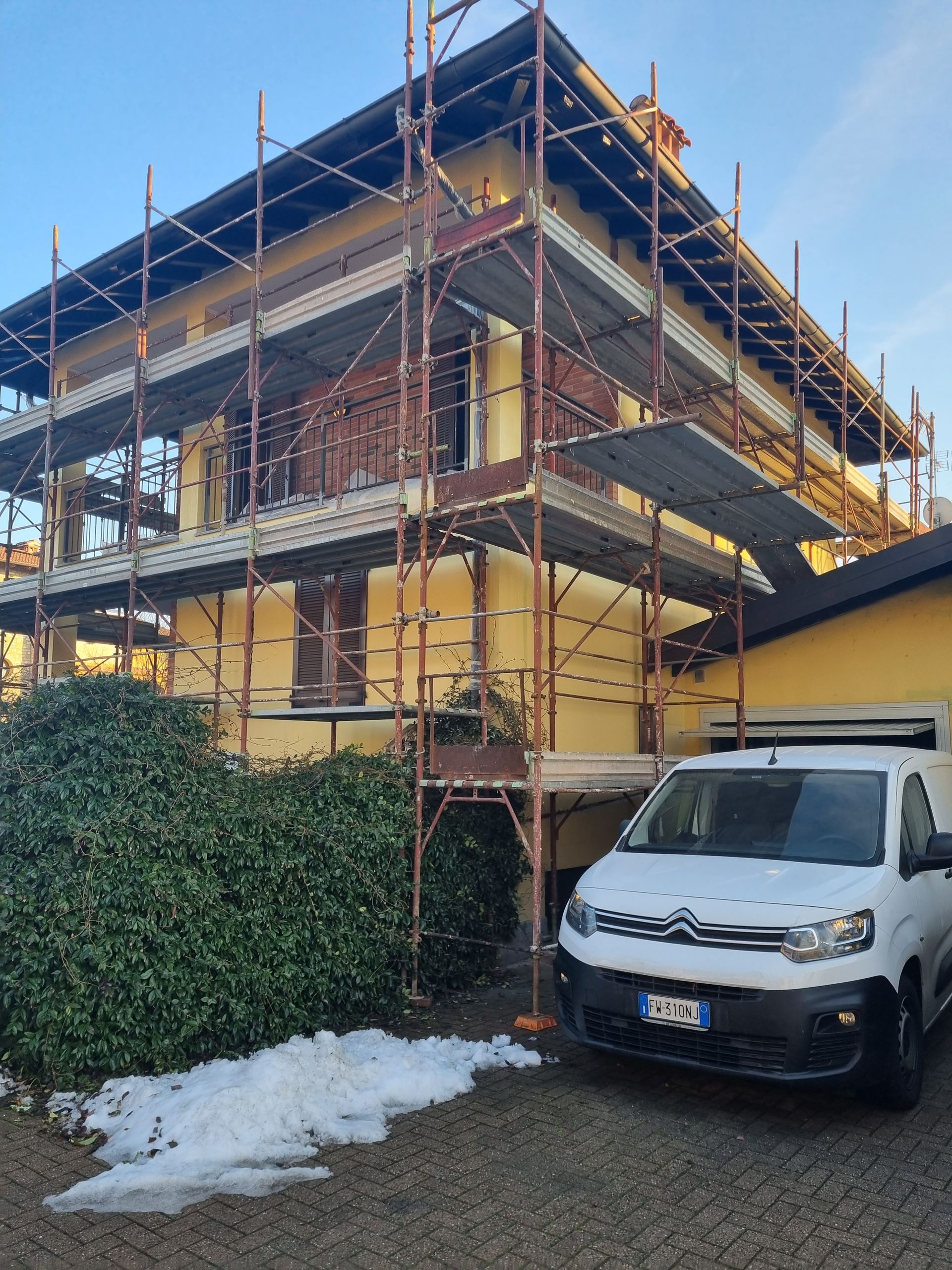 Ascensore verde che si estende fino a un alto edificio per manutenzione. Ripresa esterna in un vicolo. Cielo coperto.