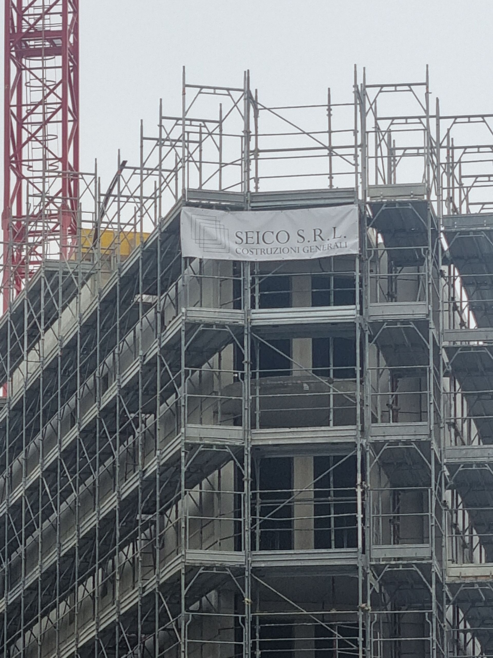 Casa in ristrutturazione, impalcature, muri gialli, furgone bianco parcheggiato davanti, neve per terra.