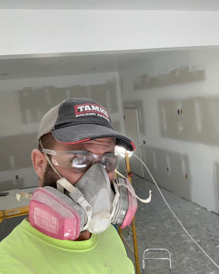 A man wearing a mask and glasses is standing in a room.