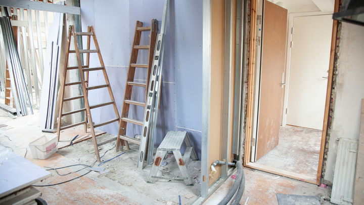 A room under construction with a ladder and a stool.