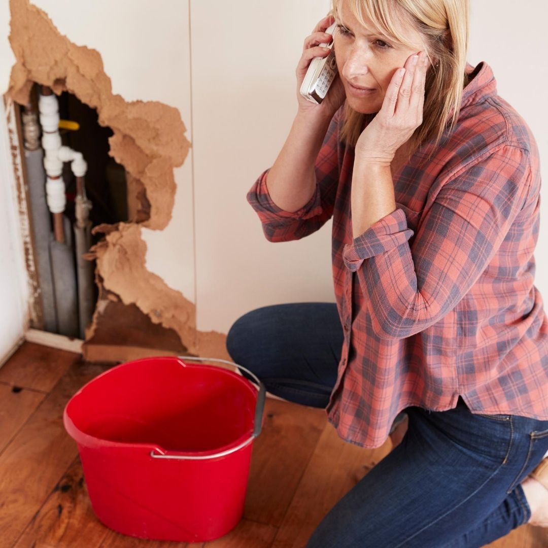 A Woman is Talking on a Cell Phone Next to a Red Bucket — Wigg Plumbing in Darwin, NT