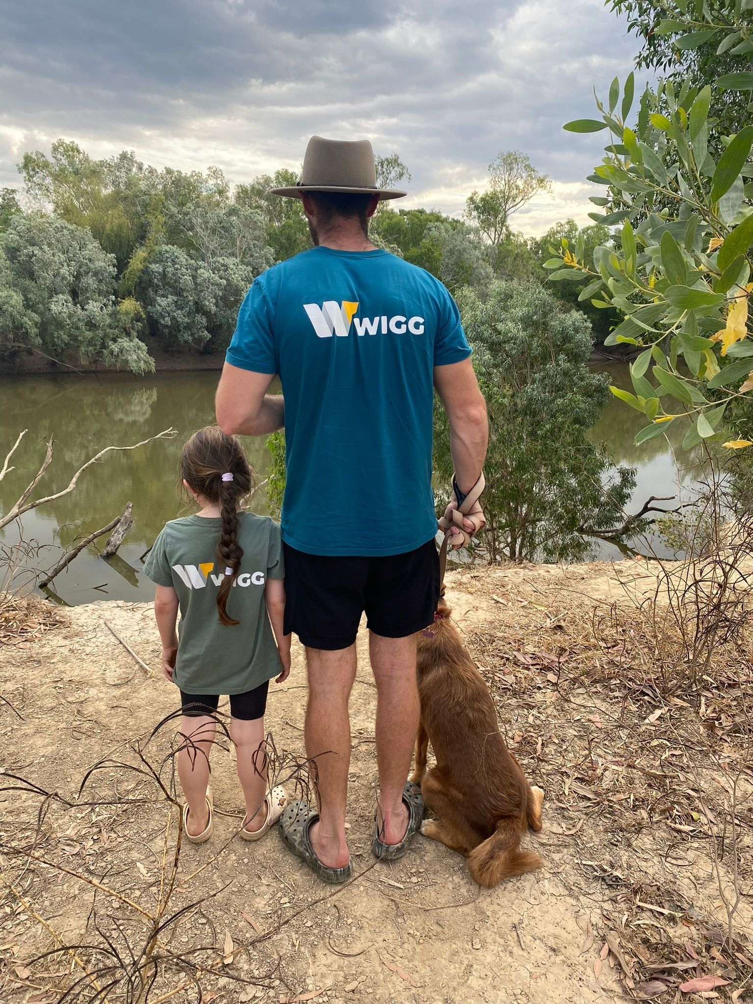 A Man with his Daughter and Dog looking out to a river — Wigg Plumbing in Berrimah, NT
