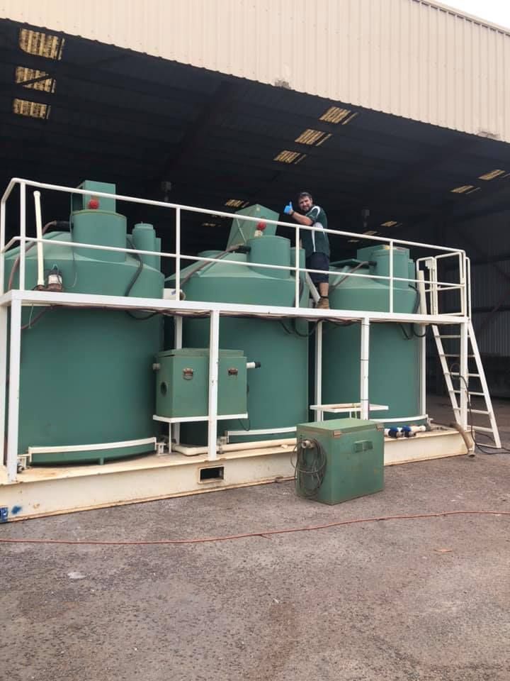 A Man is Standing on Top of a Machine in Front of a Building — Wigg Plumbing in Berrimah, NT
