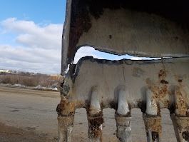 A close up of a rusty excavator bucket with a hole in it.