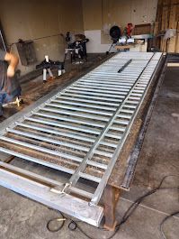 A man is working on a metal fence in a garage.
