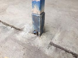 A metal pole is sitting on top of a concrete floor.