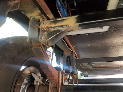 A close up of the underside of a truck with a camper underneath it.