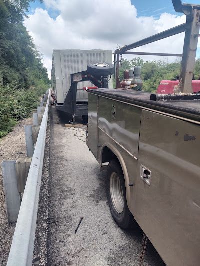 A tow truck is sitting on the side of the road next to a fence.