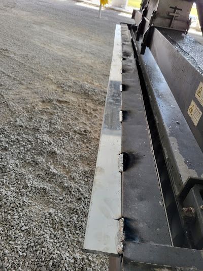 A close up of a metal railing on a gravel road.
