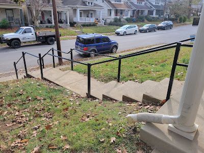 A truck is parked on the side of the road next to a set of stairs.