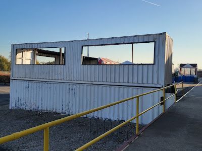 A white shipping container with a yellow railing in front of it.